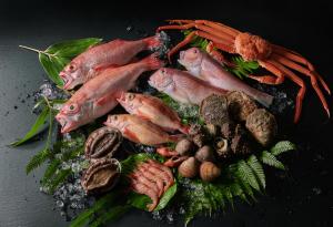 un grupo de peces y hortalizas sobre una mesa en Noto Hyakurakusou en Ogi