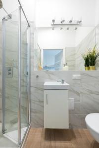 een witte badkamer met een douche en een wastafel bij Wspólna 54A - Red - Good Apartments in Warschau