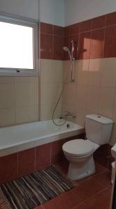 La salle de bains est pourvue de toilettes, d'une baignoire et d'une fenêtre. dans l'établissement Andris apartment, à Paralímni