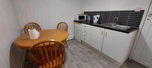 Lovely 3-Bed Apartment in Parkgate Rotherham في روثيرهام: مطبخ صغير مع طاولة وكراسي ومغسلة