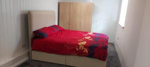 a bedroom with a bed with a red comforter and a refrigerator at Lovely 3-Bed Apartment in Parkgate Rotherham in Rotherham