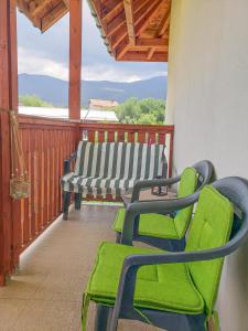 - une terrasse couverte avec des chaises vertes et un banc dans l'établissement Forest Sunrise, à Samokov