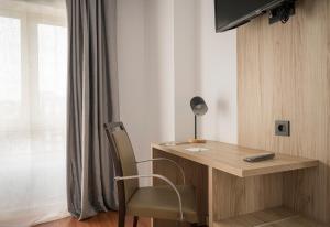 ヒホンにあるHotel Alda Centro Gijónのデスク、椅子、ランプが備わる客室です。