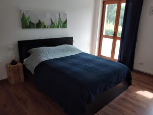 a bedroom with a bed with a blue blanket and a window at Appartamento a due passi da Burcina in Favaro