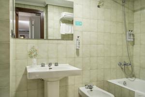 a bathroom with a sink and a toilet and a mirror at Hotel Alda Centro Gijón in Gijón