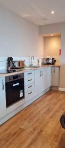 uma cozinha com armários brancos e um forno preto em The Ramleh em Scarborough
