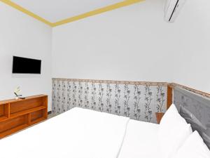 um quarto com uma cama e uma televisão na parede em OYO 91192 Homestay Antara em Gilimanuk