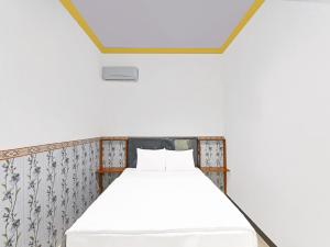 a white bed in a room with a ceiling at OYO 91192 Homestay Antara in Gilimanuk