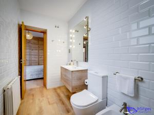 a white bathroom with a toilet and a sink at InSitges Ribera's Beach in Sitges