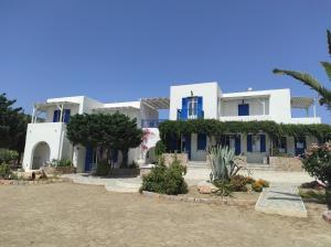 Casa blanca grande con ventanas azules y arbustos en Villa Le Grand Bleu, en Katápola
