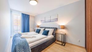 a bedroom with a large bed with blue pillows at Apartamenty Sun & Snow Aquarius in Kołobrzeg