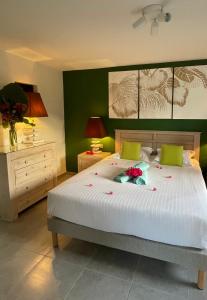 a bedroom with a large white bed with green walls at Ti Verger in Sainte-Luce