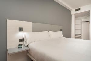Hotel Alda Centro Gijón في خيخون: غرفة نوم بسرير ابيض كبير ونافذة