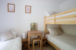 two beds in a room with a desk and a bunk bed at 4 Bedroom Cottage with panoramic Harbour views in Falmouth