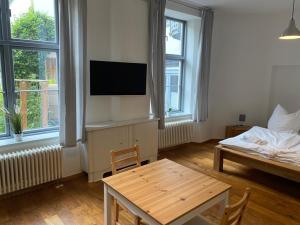 ein Wohnzimmer mit einem TV, einem Tisch und einem Bett in der Unterkunft Sunfe in Stralsund