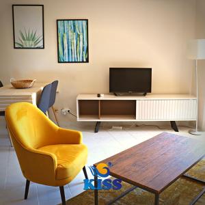 a living room with a tv and a chair and a table at Kiss - Apartamentos Turísticos in Albufeira