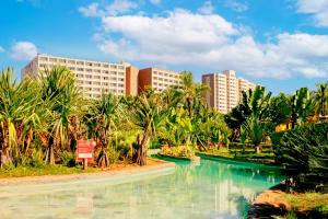 uma piscina de água com palmeiras e edifícios em Hot Beach Resort em Olímpia