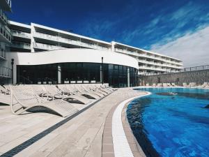 a hotel with a pool and lounge chairs next to a building at Apartament Polanki Aqua A408 in Kołobrzeg