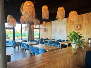 a restaurant with tables and blue chairs and chandeliers at Apartament Polanki Aqua A408 in Kołobrzeg