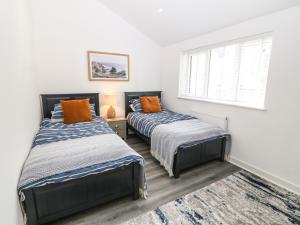a bedroom with two beds and a window at 3 Yr Hen Lys in Pwllheli