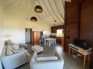 a living room with two white couches and a kitchen at La Passerelle 1 in Sainte-Rose