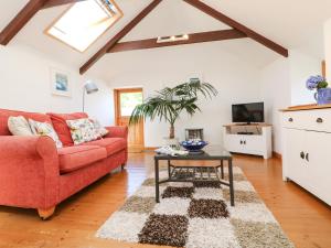a living room with a red couch and a table at Lower Rissick Cottage in Penzance