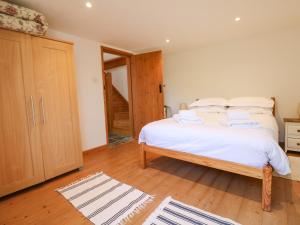 Schlafzimmer mit einem Bett mit weißer Bettwäsche und Holzböden in der Unterkunft Lower Rissick Cottage in Penzance