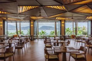 a restaurant with tables and chairs and large windows at Oceanfront Beach Resort - SHA Extra Plus in Patong Beach