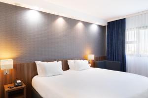 een hotelkamer met een groot bed met witte kussens bij Holiday Inn Express - Marseille Airport, an IHG Hotel in Vitrolles