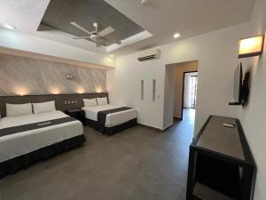 um quarto de hotel com 2 camas e uma ventoinha de tecto em Aspira Hotel Playa del Carmen em Playa del Carmen