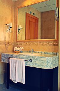 een badkamer met een wastafel, een spiegel en handdoeken bij Hotel Equo Aranjuez in Aranjuez