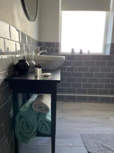 a bathroom with a sink and a table with towels at Devonshire Bungalow - close to the Coast & Lakes. in Cleator