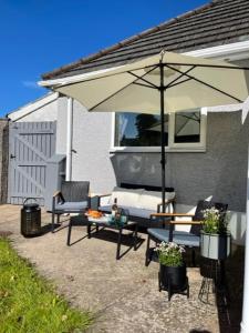une terrasse avec un parasol, des chaises et une table dans l'établissement Devonshire Bungalow - close to the Coast & Lakes., à Cleator