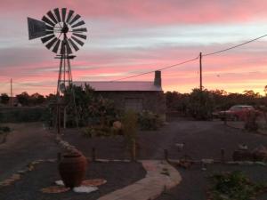 a windmill sitting next to a building with a sunset at Die Stal in Sutherland