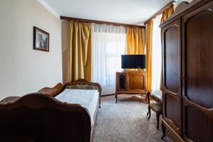 um quarto com uma cama, uma cómoda e uma televisão em Hotel Polonia em Toruń