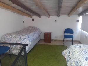 sypialnia z 2 łóżkami i niebieskim krzesłem w obiekcie VILLA DE MONTAÑA LOS CHACAYES, Manzano Hitorico, Caminos del vino, ruta 94 w mieście Tunuyán