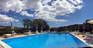 a large blue swimming pool with chairs and umbrellas at Agriturismo Feudo Gagliardi in Caulonia
