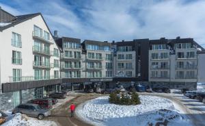 ein Mann steht vor einem Gebäude im Schnee in der Unterkunft Aparthotel Apartamenty Czarna Góra 227 in Heudorf + 19 Fotos