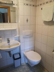 a white bathroom with a toilet and a sink at Pension Schlager Taxerhof in Bad Hofgastein