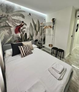a bedroom with a large white bed with a mural on the wall at Apartamento Lucano in Córdoba