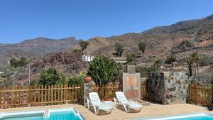 eine Terrasse mit Stühlen und einen Pool mit Bergen im Hintergrund in der Unterkunft casa rural LA LIMERA con piscina privada in Santa Lucía