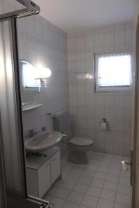 La salle de bains blanche est pourvue de toilettes et d'un lavabo. dans l'établissement Apartments Ruža Mikelić, à Rab