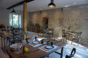 un restaurant avec des tables et des chaises en bois et un mur en briques dans l'établissement Le Moulin de Moquesouris - Chambres d'hôtes et table d'hôte, à Nazelles-Négron