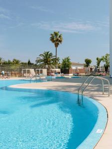 a swimming pool with blue water and palm trees at Bordoy Alcudia Bay - Adults Only in Port d'Alcudia