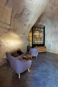 a living room with a couch and chairs and a table at Grotta Barisano in Matera