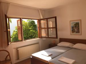 um quarto com uma cama e duas janelas em Apartments Ruža Mikelić em Rab