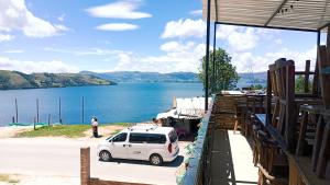 a white car parked next to a body of water at Hospedaje Puerta al Lago in Suse