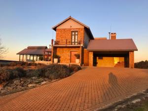 a house with a brick driveway in front of it at Vetho Farmhouse Dullstroom in Dullstroom