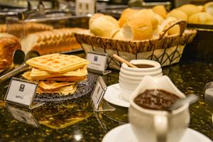 uma mesa coberta com pão e waffles e um prato de comida em Comfort Hotel Bauru em Bauru