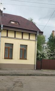 a yellow house with a brown roof at Apartment near University in Chernivtsi